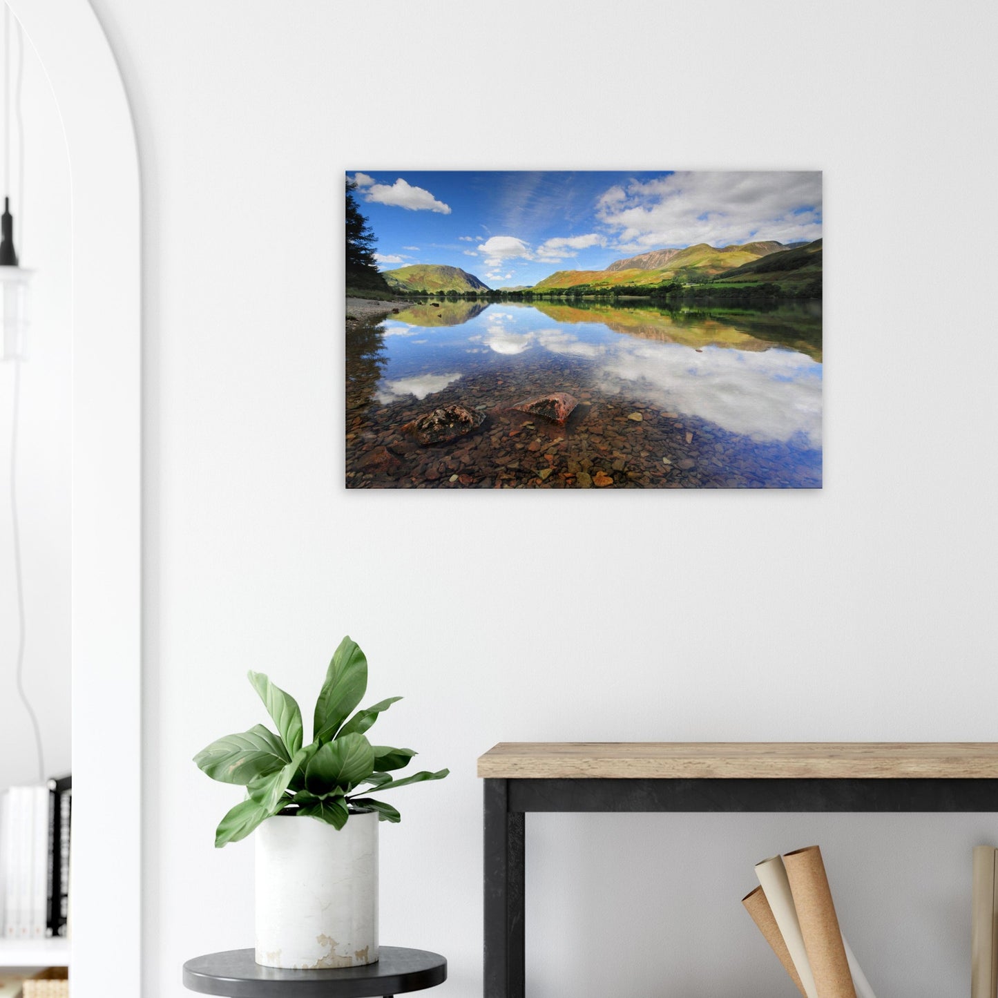 Calm and clear canvas print of Buttermere Lake, with sunlight illuminating the landscape and sky reflected in the still, transparent water.