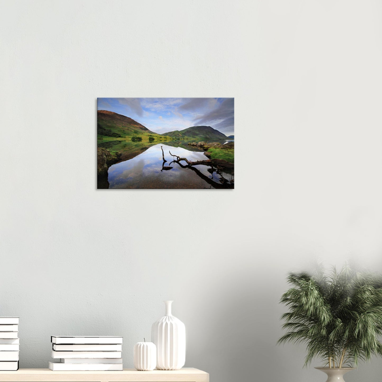 Lake District canvas print of Crummock Water showing a still lake surface, a single branch in the foreground, and soft reflections of fells and sky.