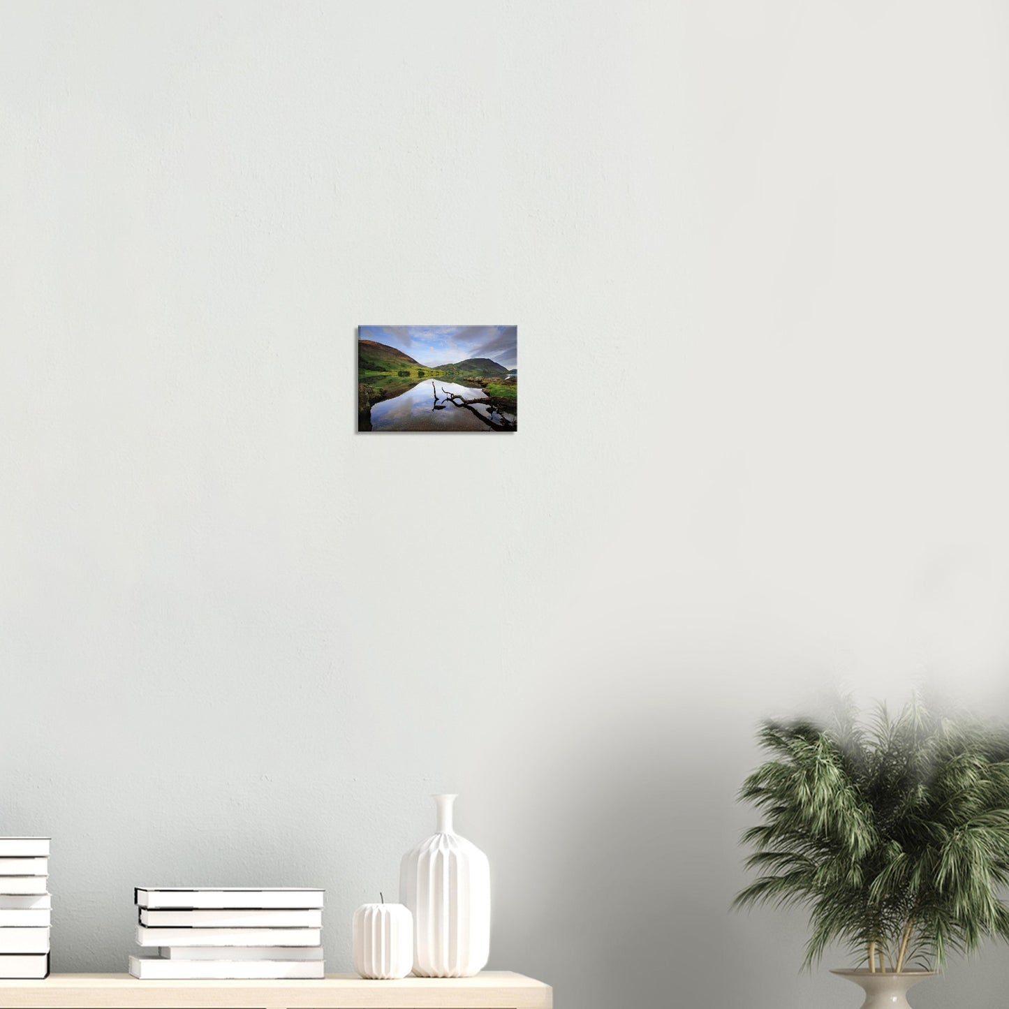 Reflective canvas artwork of Crummock Water featuring a lone branch in clear, calm water with reflections of gentle fells and a soft cloudy sky.