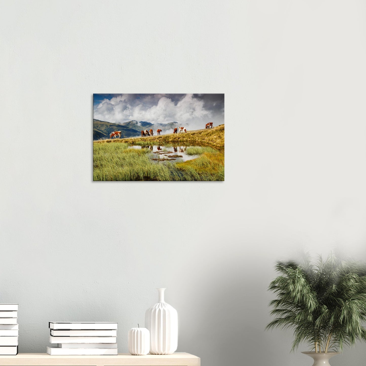 Pastoral mountain scene in canvas form with cows grazing near a small alpine lake and dramatic peaks emerging through clouds.