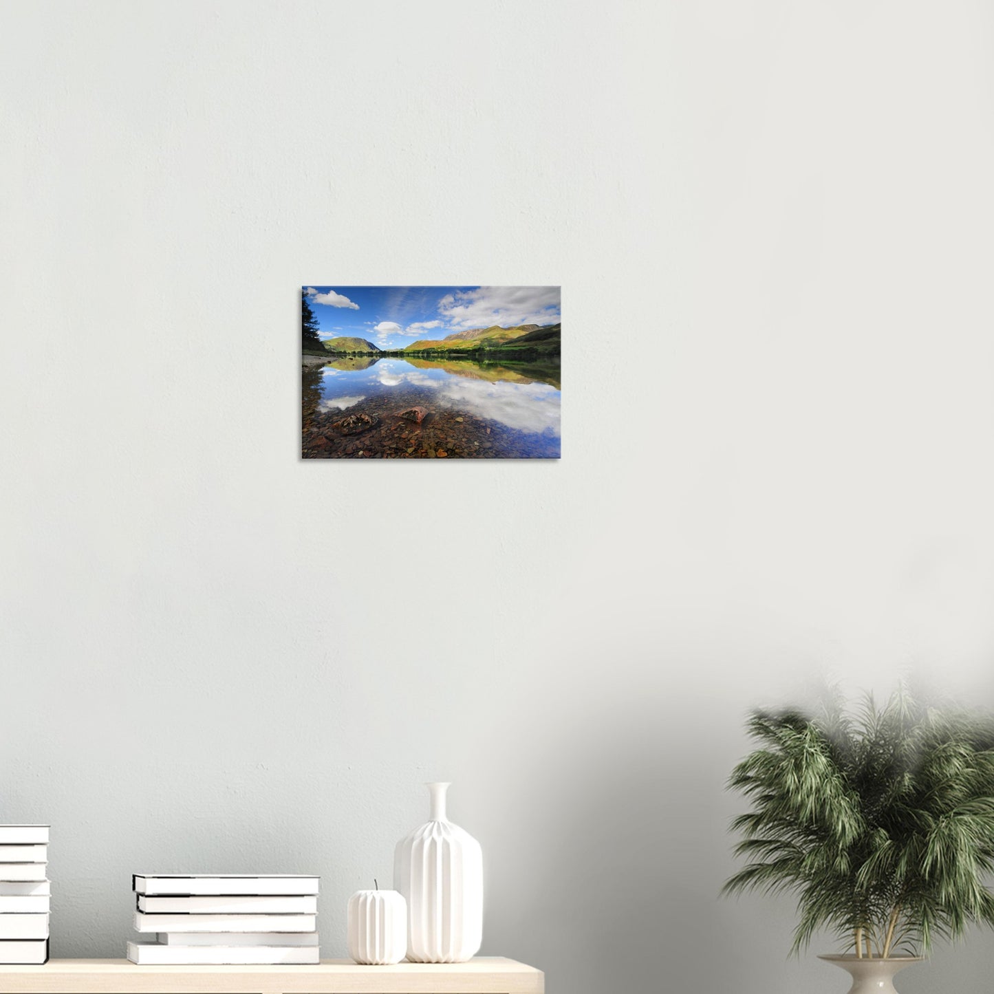 Scenic canvas print featuring Buttermere Lake’s undisturbed clarity with underwater pebbles and a mirrored view of fells and white clouds.