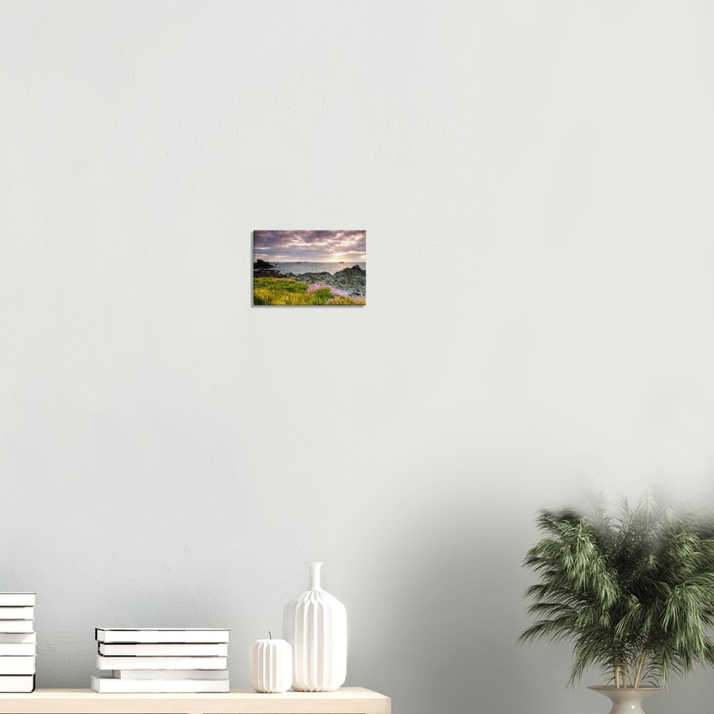 Dramatic sunset canvas print from Guernsey featuring Les Hanois Lighthouse beyond rugged rocks and flower-strewn coastal grass.