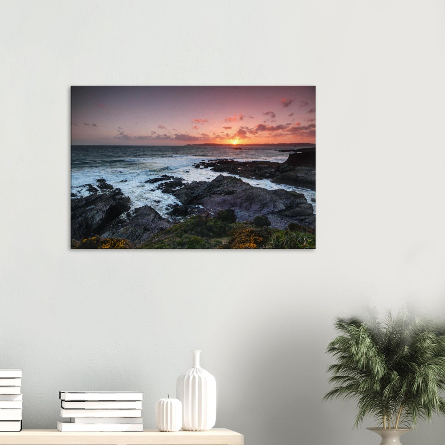 Heybrook Bay canvas print showcasing a glowing sea and silhouetted cliffs bathed in warm sunset light with wildflowers on the cliffs.