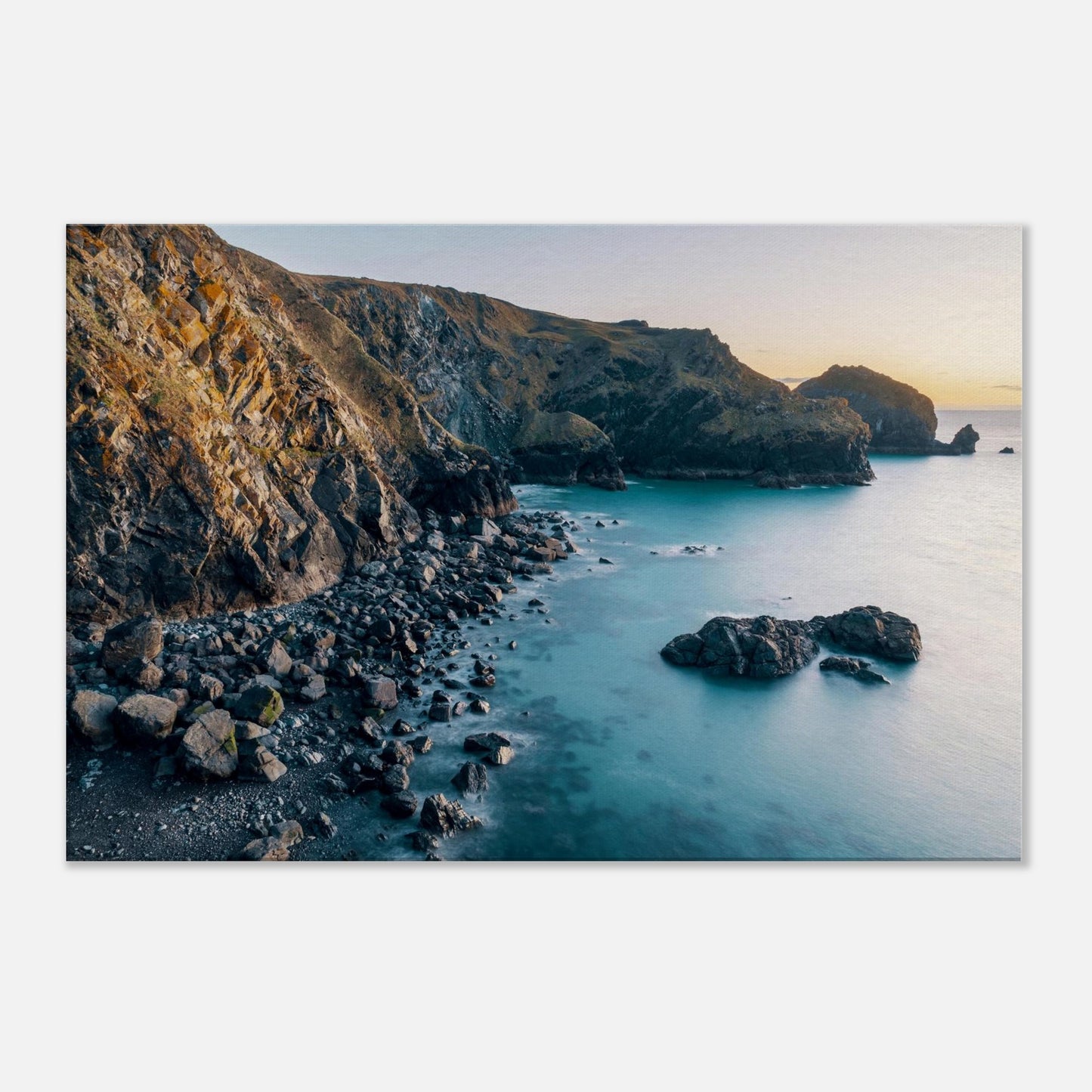 Peaceful evening scene at Mullion Cove with soft golden tones reflecting on the sea