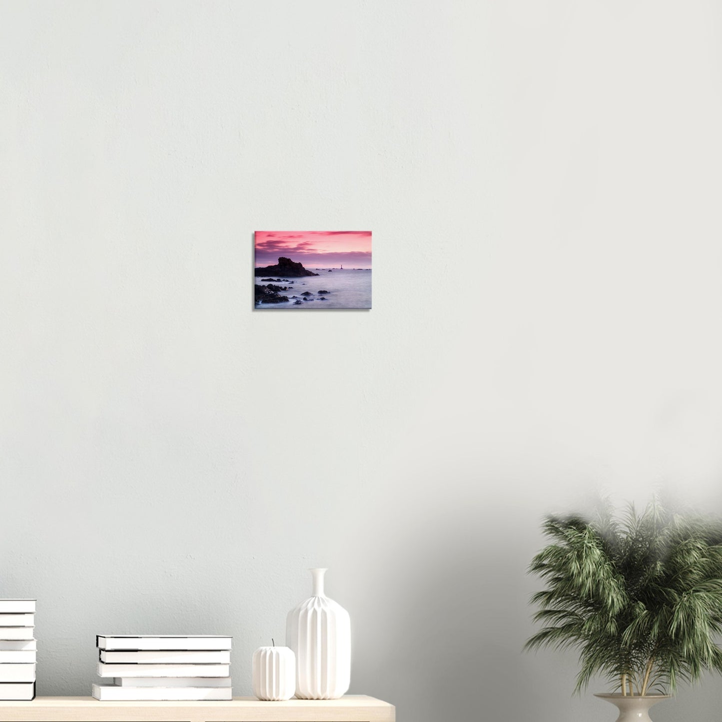 Sunset wall art of Guernsey’s Les Hanois Lighthouse, with dramatic skies and smooth sea framed by rocky shores.