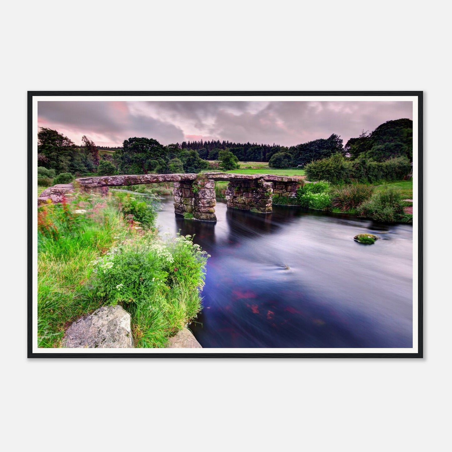 Historic stone clapper bridge over gentle river in Dartmoor