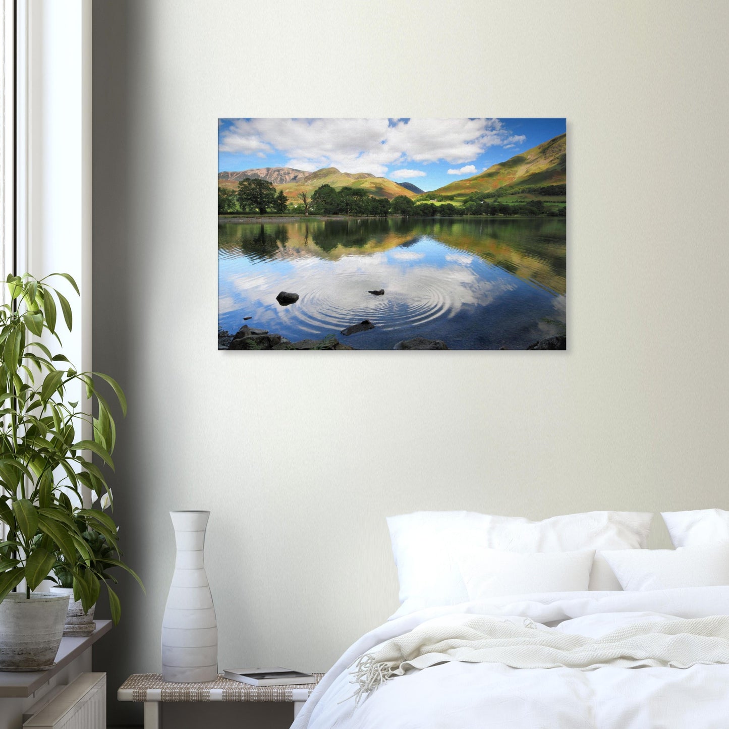 Canvas print of Buttermere Lake at rest, disturbed only by the ripple from a thrown stone, with green fells and blue sky reflections.