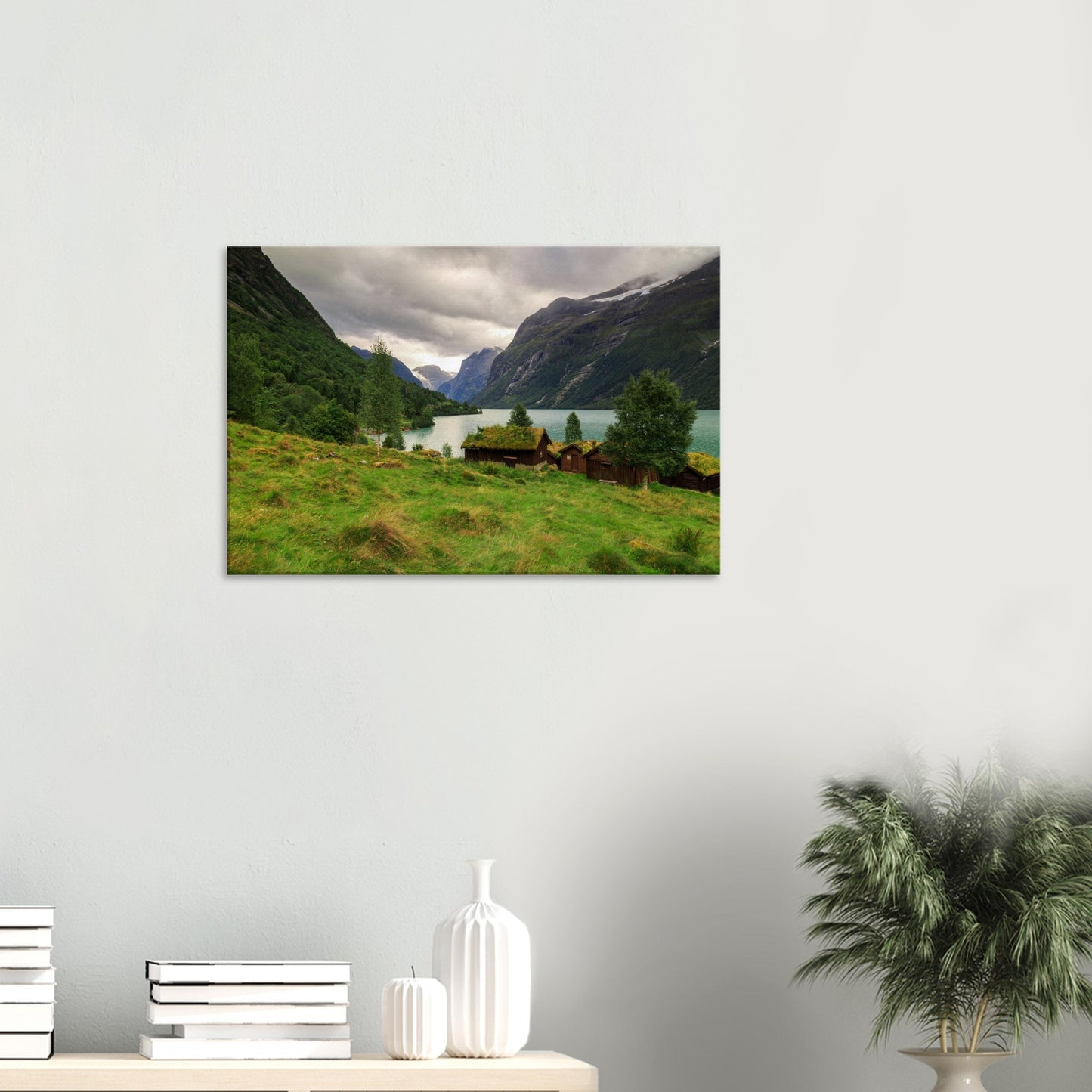 Peaceful Norwegian valley scene printed on canvas featuring grass-roofed cabins, turquoise lake, and towering cliffs.