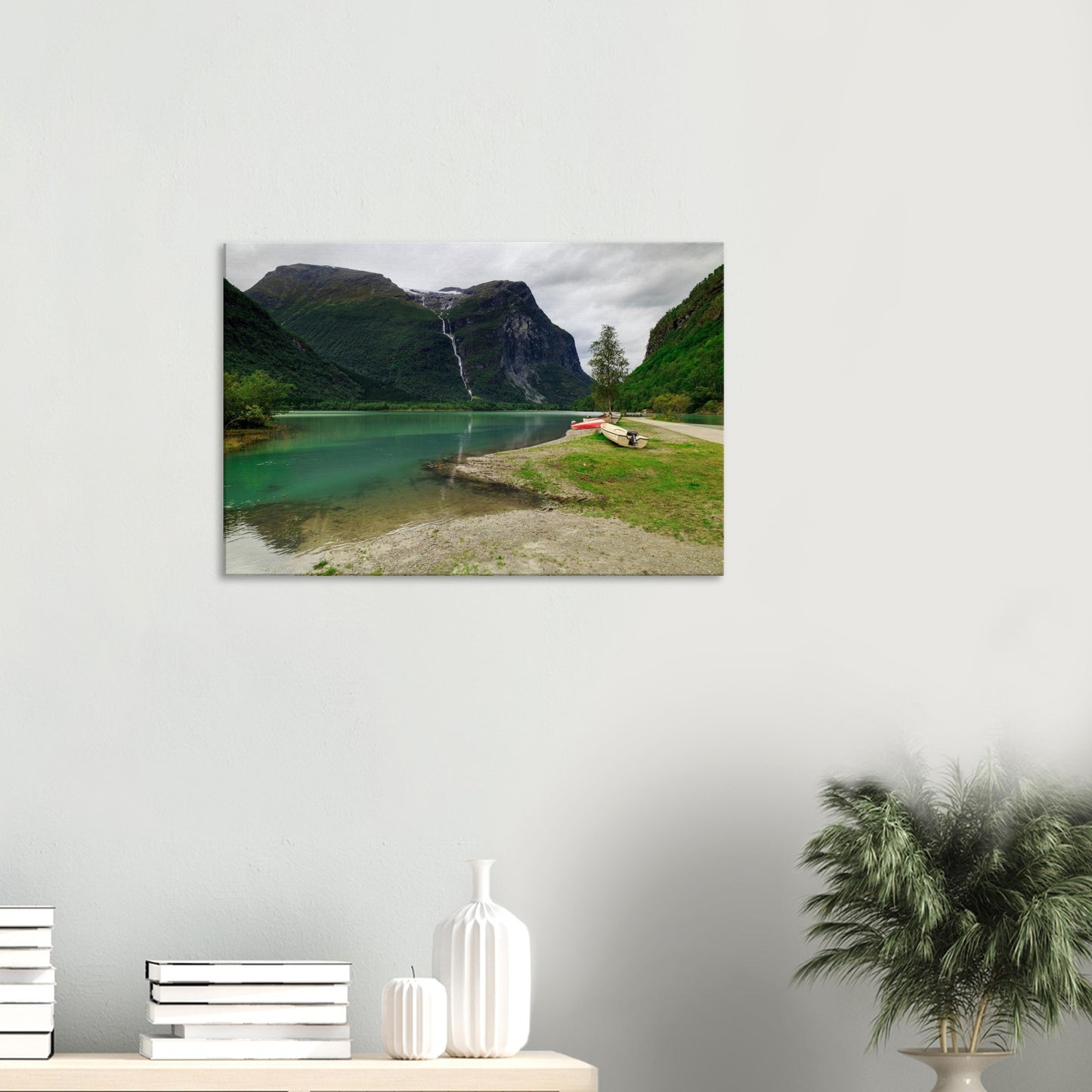 Boats resting peacefully on the shore of a calm lake surrounded by towering mountains and lush vegetation