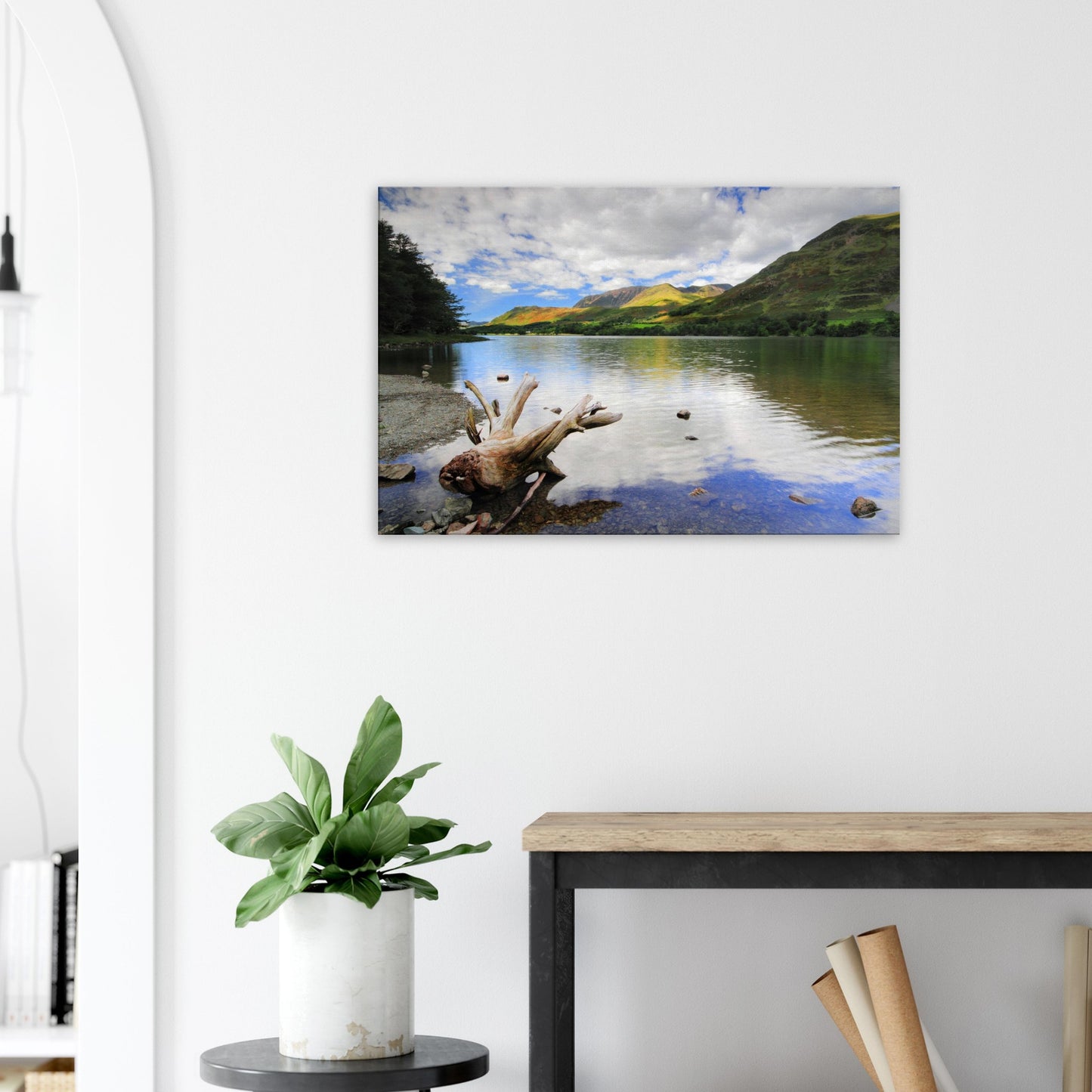 Canvas artwork capturing the serene atmosphere of Buttermere Lake with smooth reflective waters, driftwood, and sunlit fells in the background.