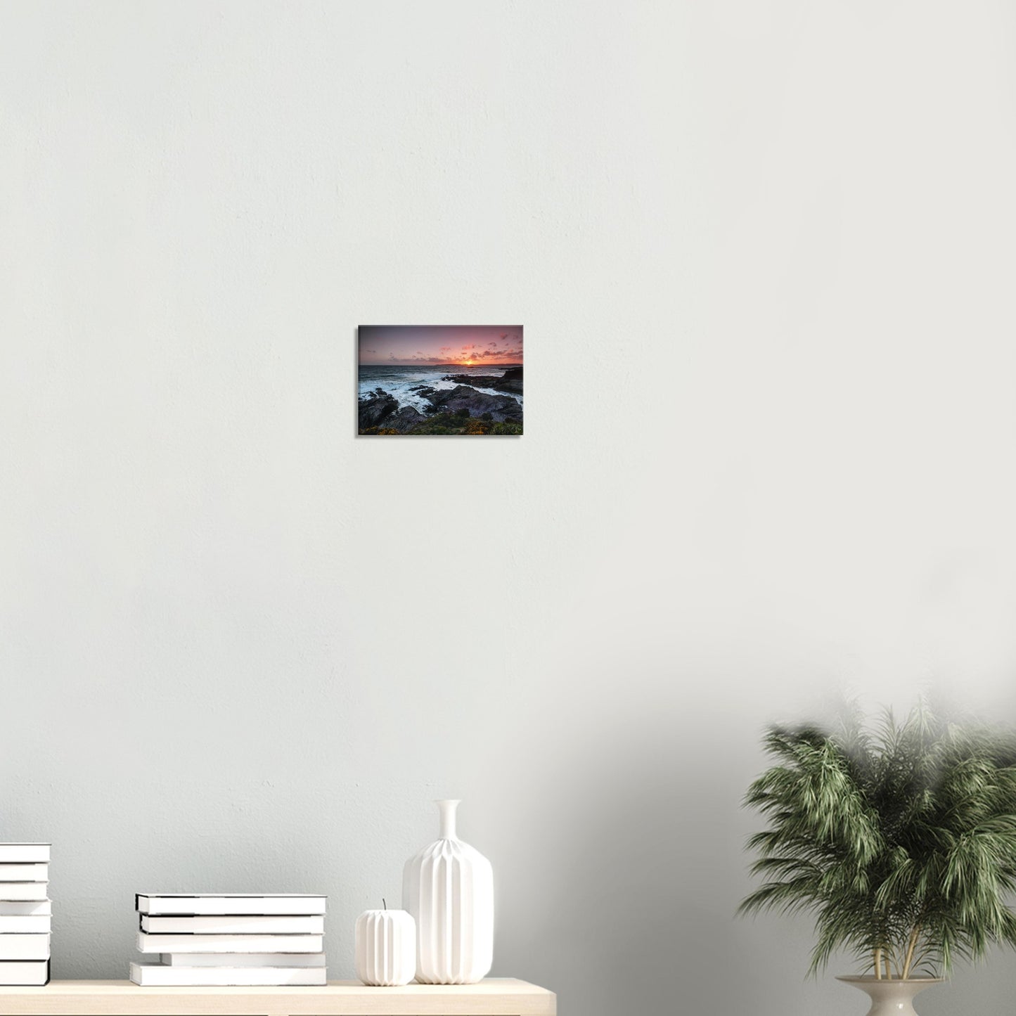 Canvas print depicting Heybrook Bay’s sunset scene with warm light reflecting on the churning sea and wildflowers on a windswept cliff.