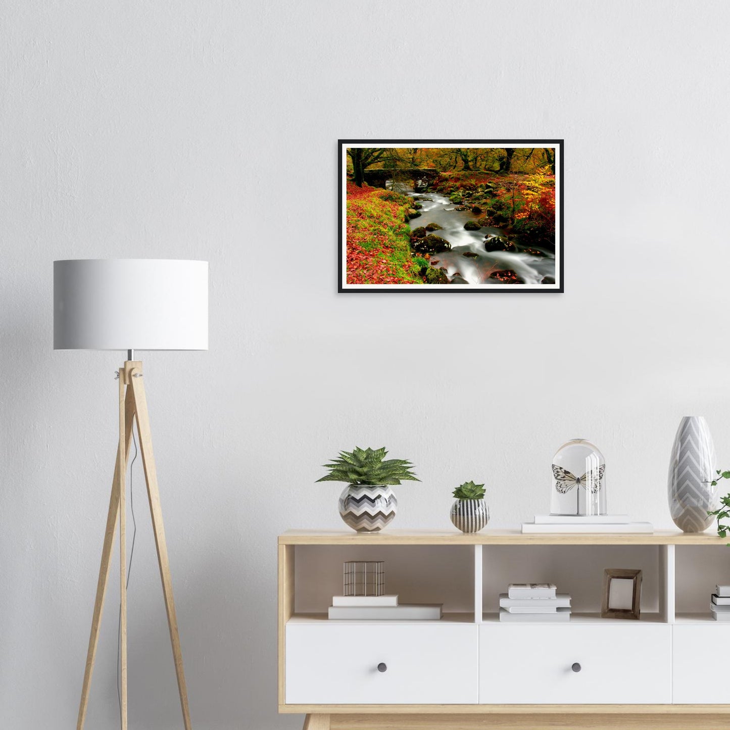 Autumn woodland landscape with flowing stream and stone bridge