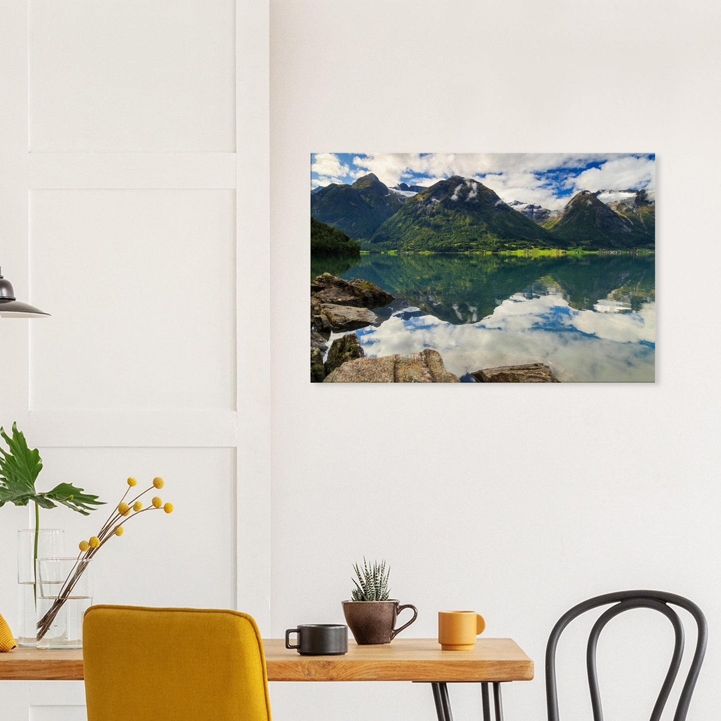 Calm lake water offering flawless reflections of the dramatic mountain landscape and soft clouds above