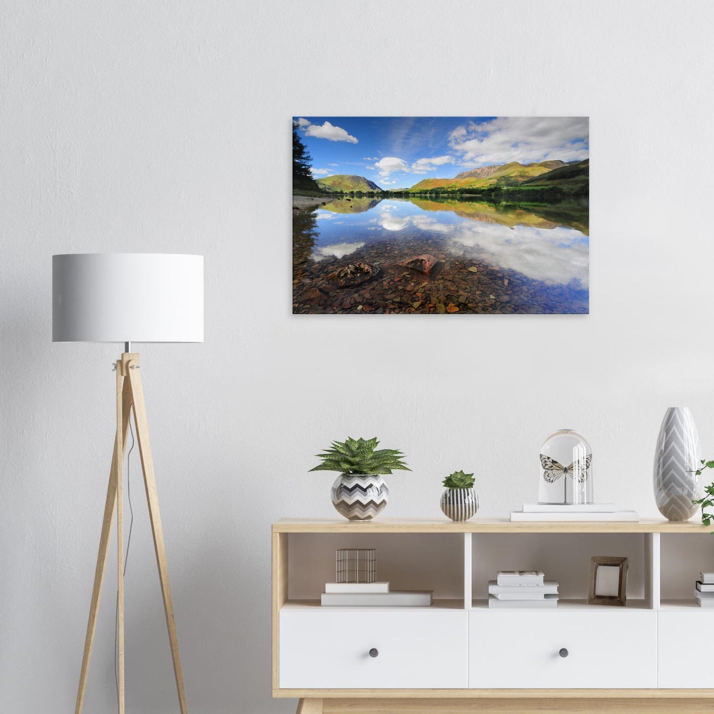 Canvas print of Buttermere Lake in the Lake District with serene reflections of the sky and fells on clear water revealing a stony lakebed.