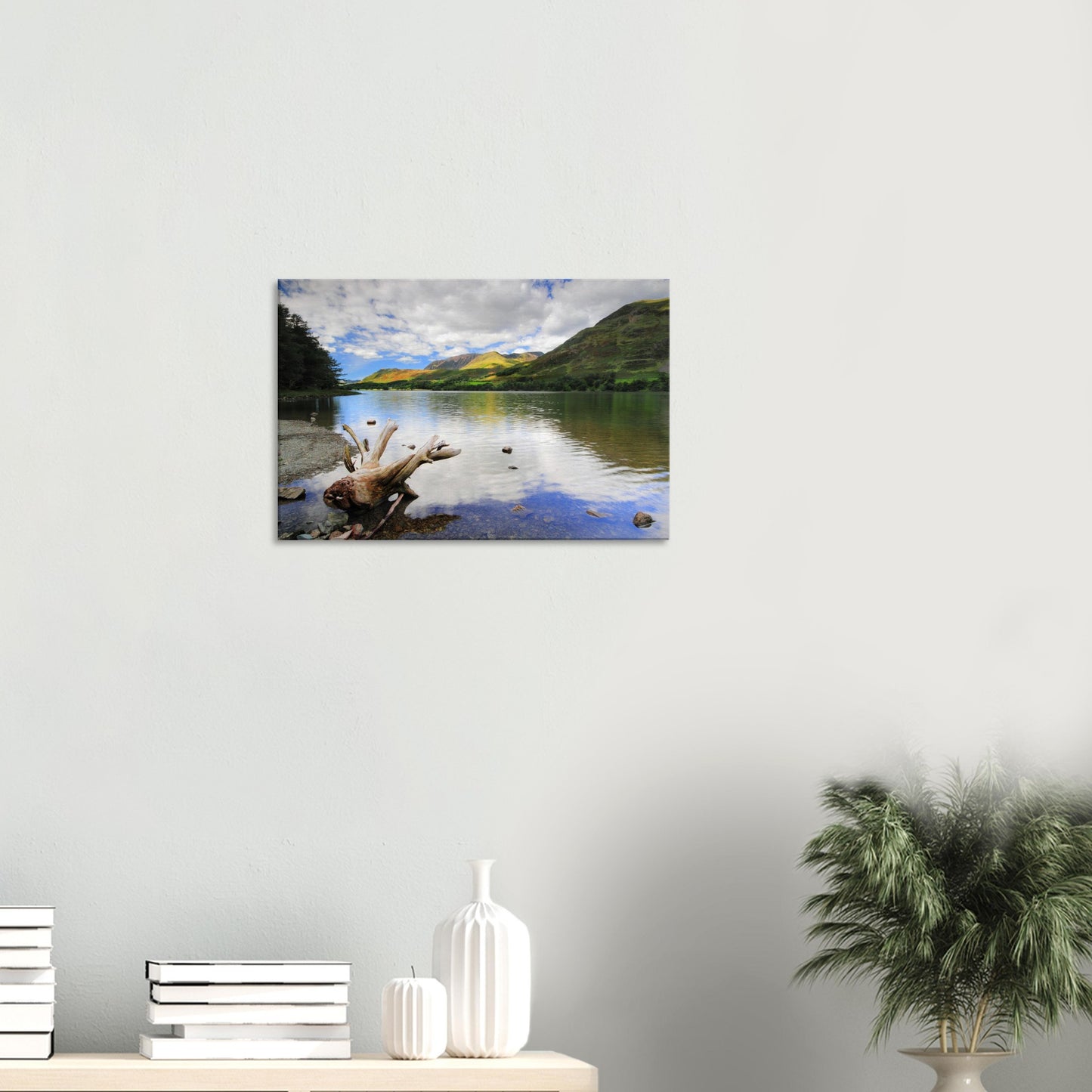Reflective landscape canvas of Buttermere Lake featuring smooth water, fluffy clouds reflected, and weathered driftwood resting near the shore.