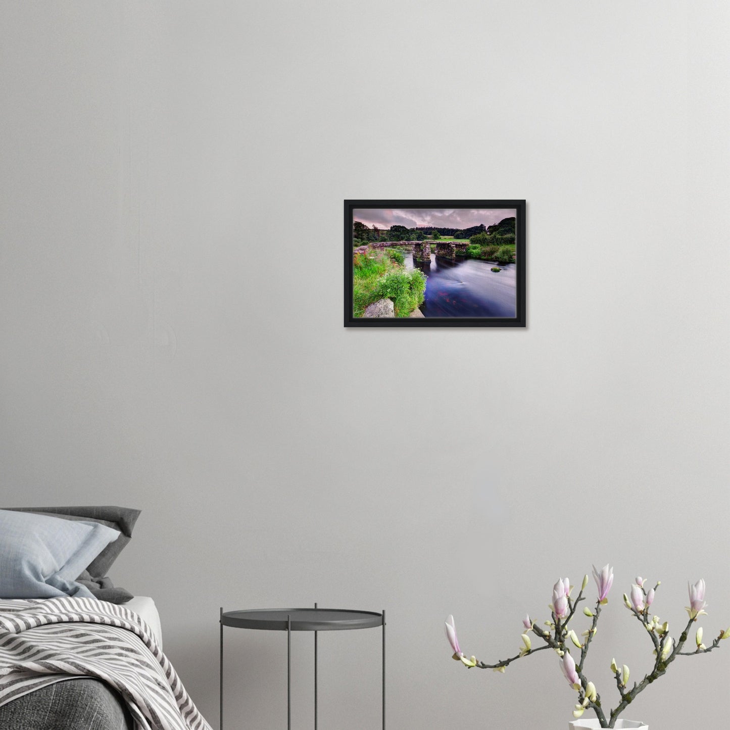 Clapper bridge over river with wildflowers in framed canvas print