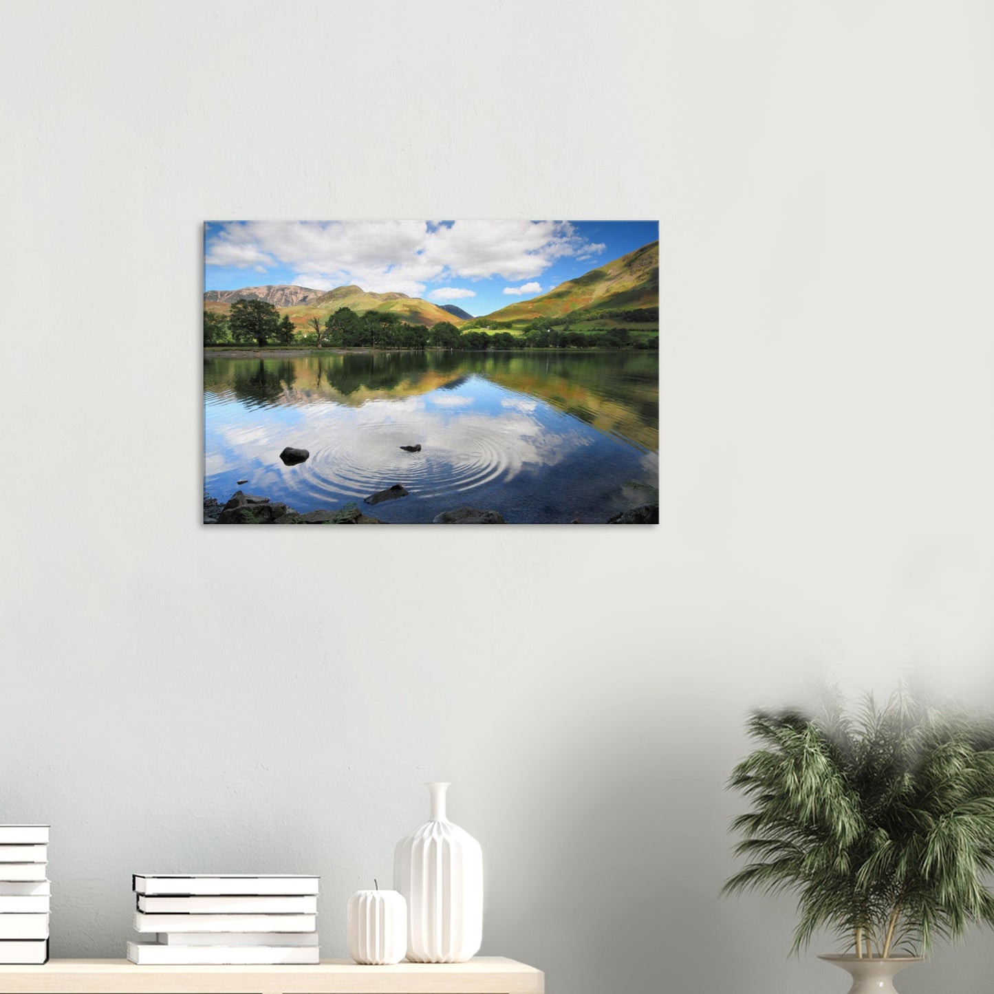 Peaceful landscape canvas of Buttermere Lake showing ripples from a skipped stone across reflective waters framed by sunlit green hills.