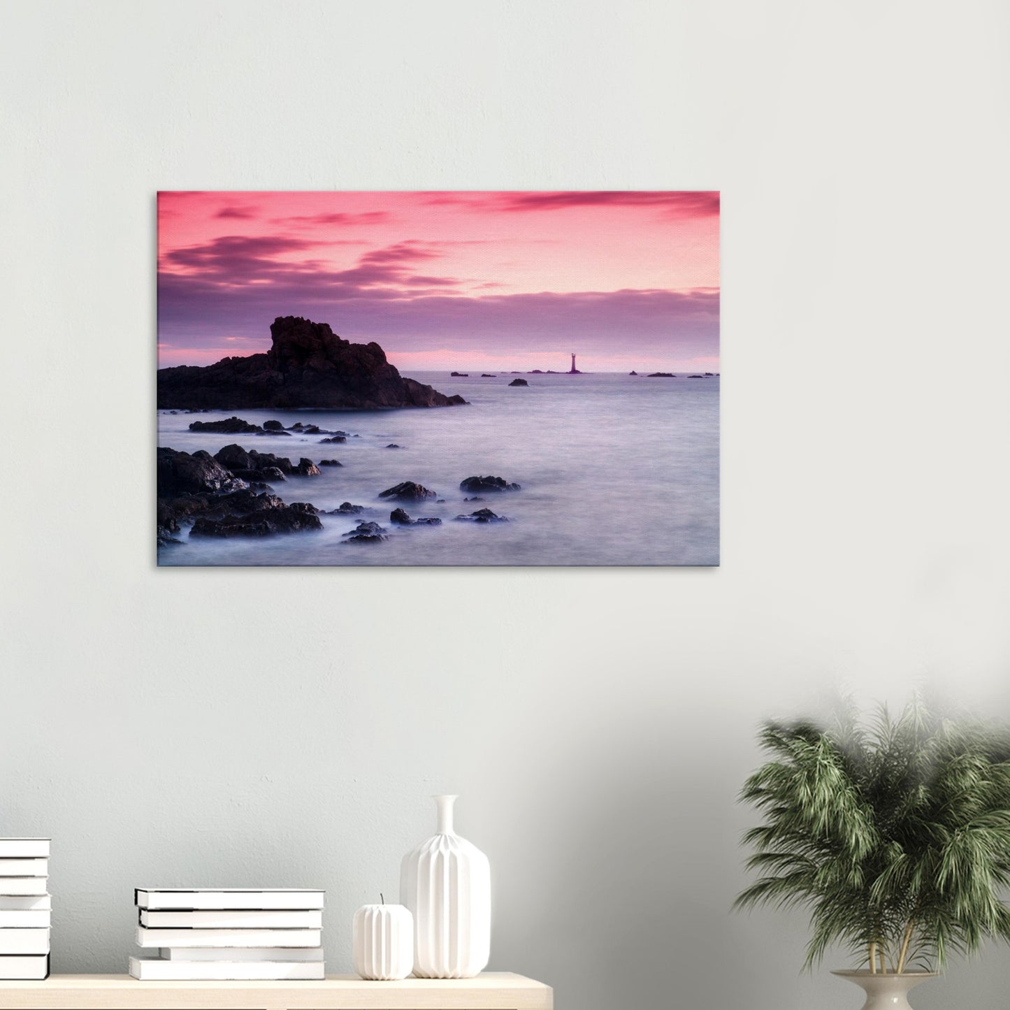 Canvas print of Les Hanois Lighthouse at sunset in Guernsey, silhouetted against a pink and purple sky above a calm sea.