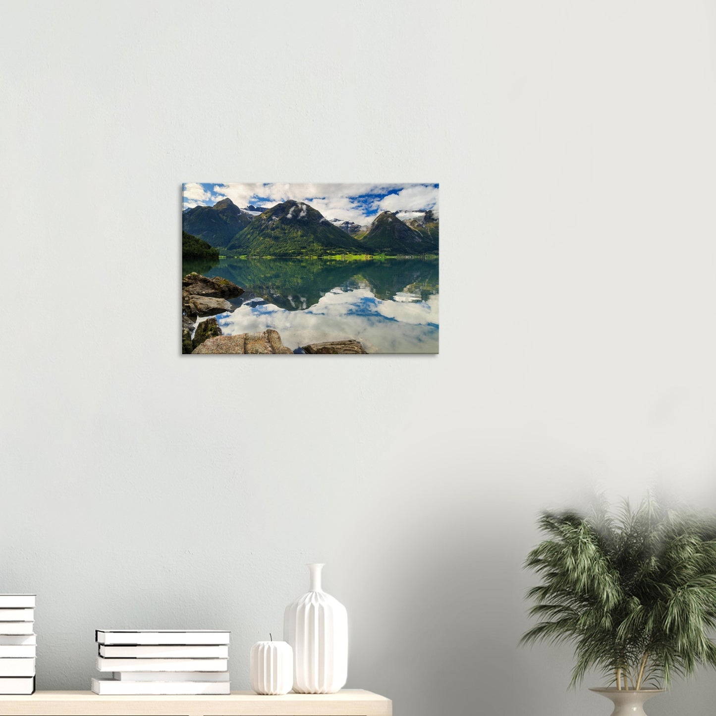 Foreground rocks leading the eye across glassy lake to verdant greenery on steep mountain slopes