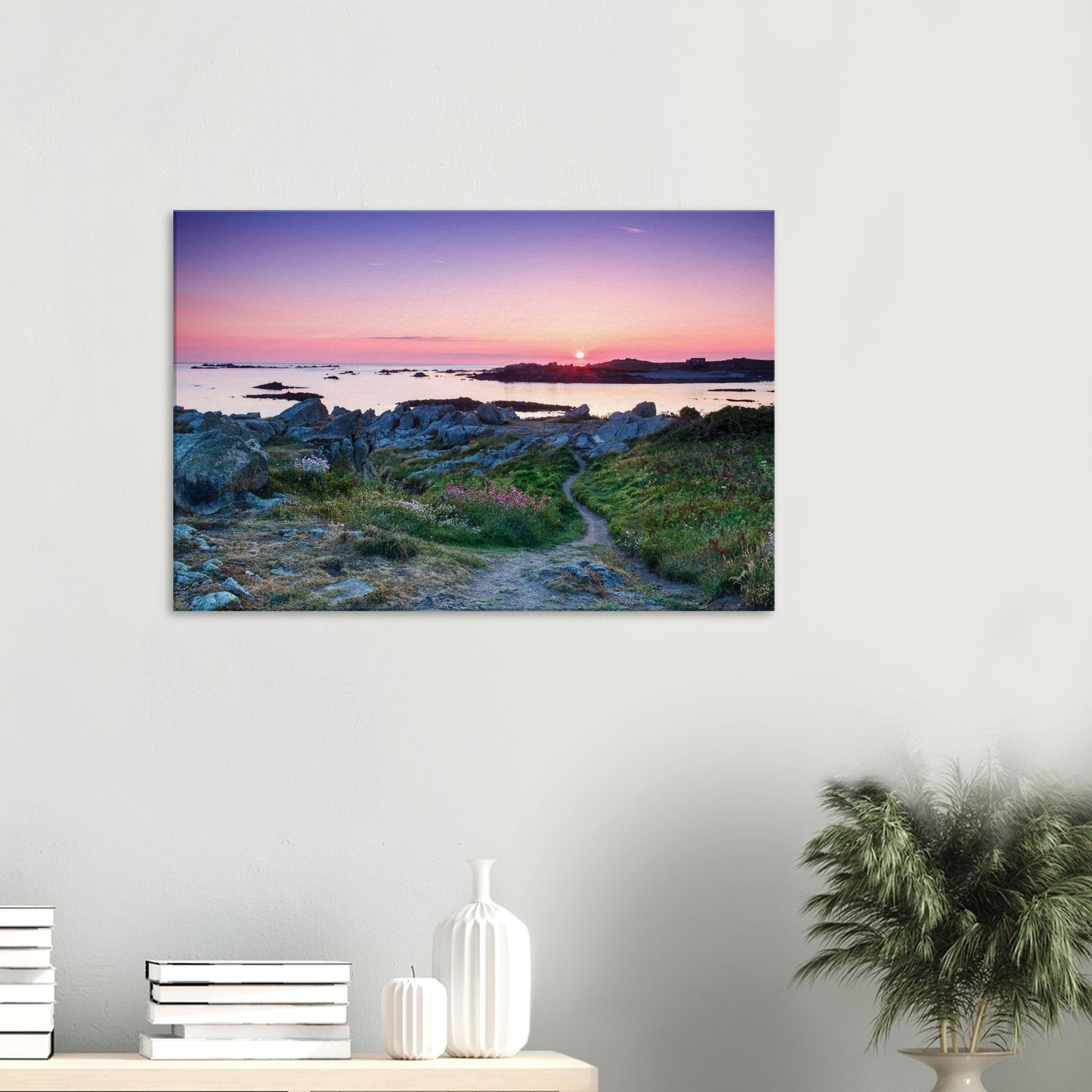 Canvas print of Guernsey’s Lihou Island with a tranquil footpath, wildflowers, and tide pools lit by golden sunset rays.