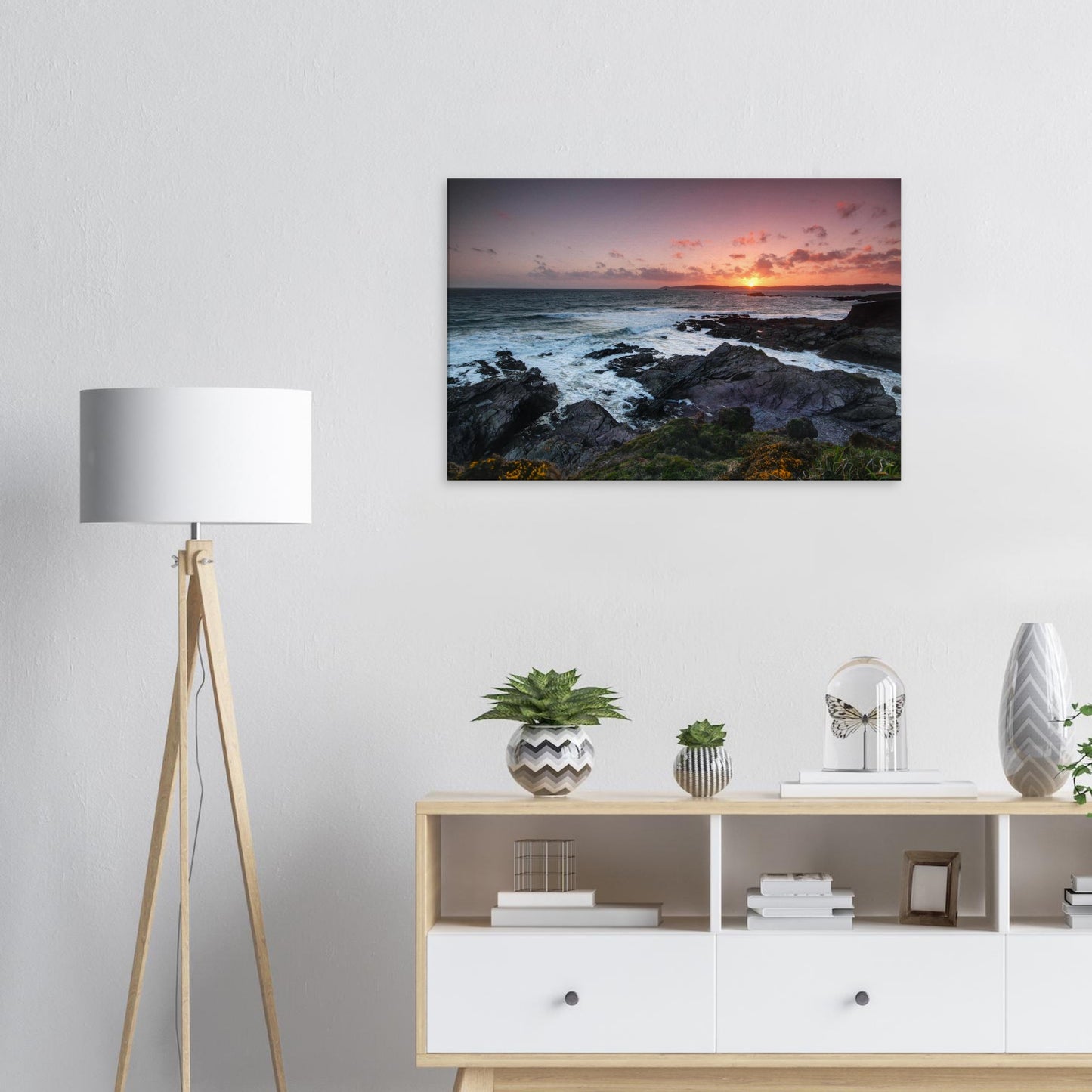 Canvas artwork of Heybrook Bay at dusk with a glowing golden sky, silhouetted rocky shore, and wildflowers swaying in the breeze.