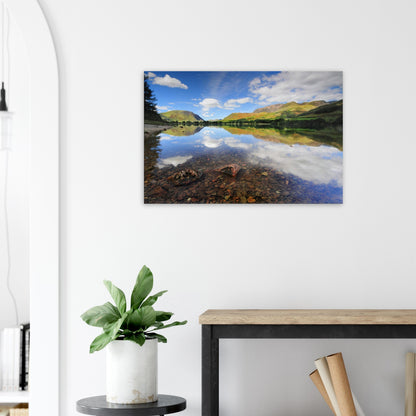 Calm and clear canvas print of Buttermere Lake, with sunlight illuminating the landscape and sky reflected in the still, transparent water.