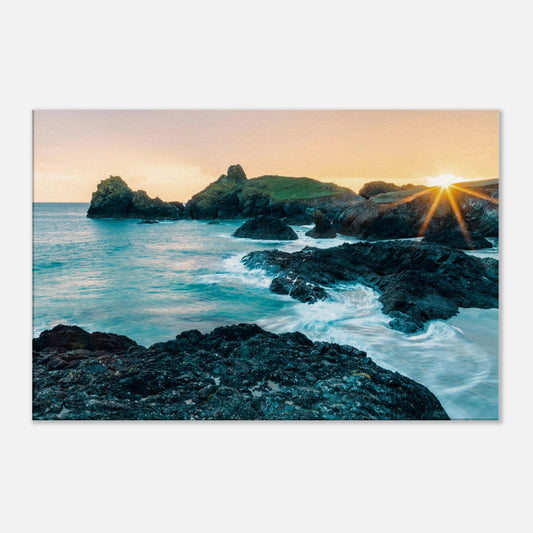 Radiant sun dipping behind the headland at Kynance Cove, casting reflections on the sea