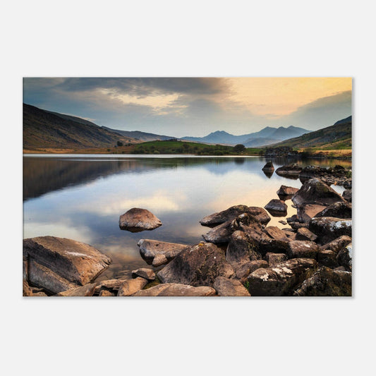 Peaceful Snowdonia lake scene with rocks breaking water surface and distant mountain silhouettes