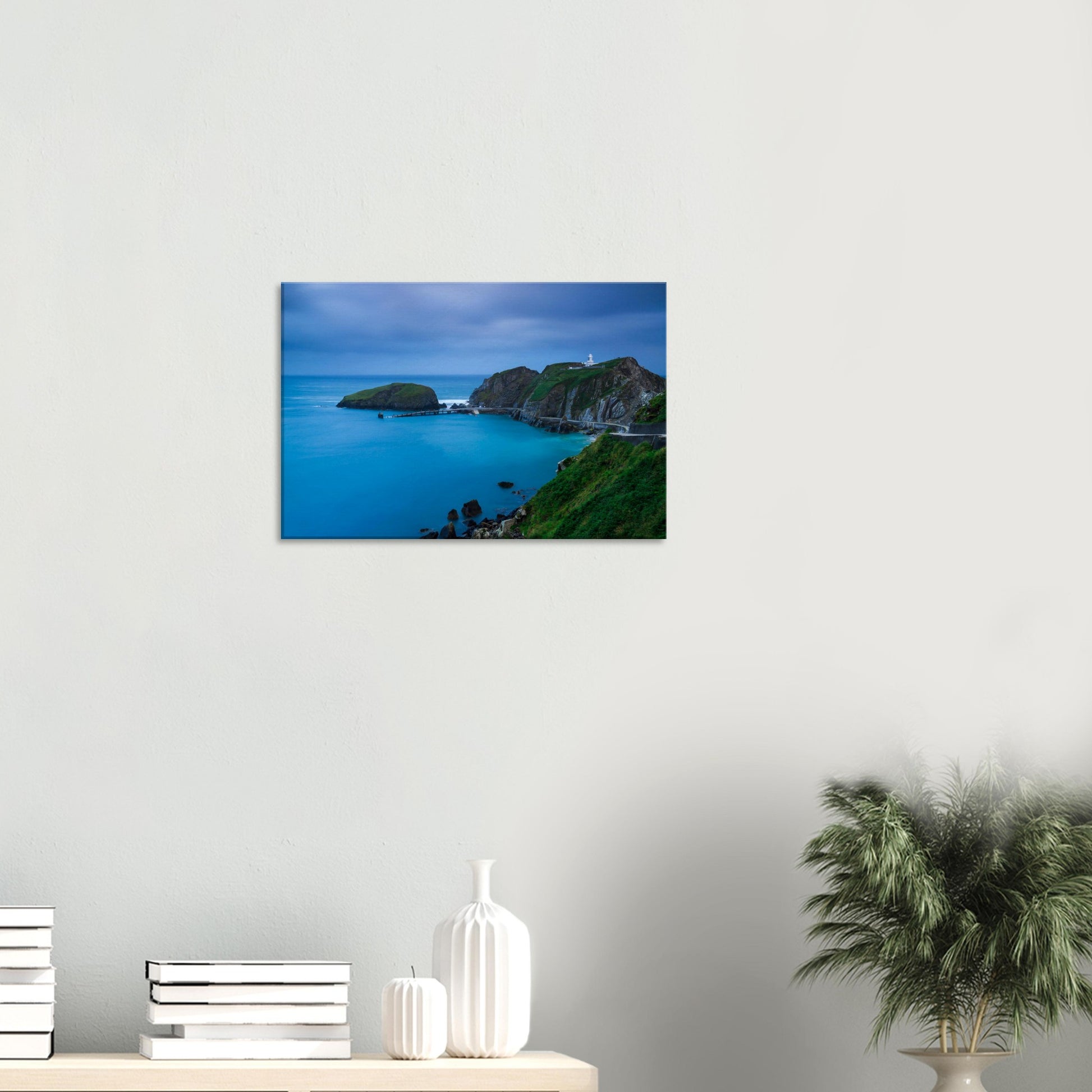 Moody dusk canvas print of Lundy Island with a calm bay, rocky cliffs, and the iconic lighthouse glowing softly in fading light.