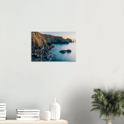 Tranquil coastal landscape in Cornwall as sunset bathes the cove in warm afterglow