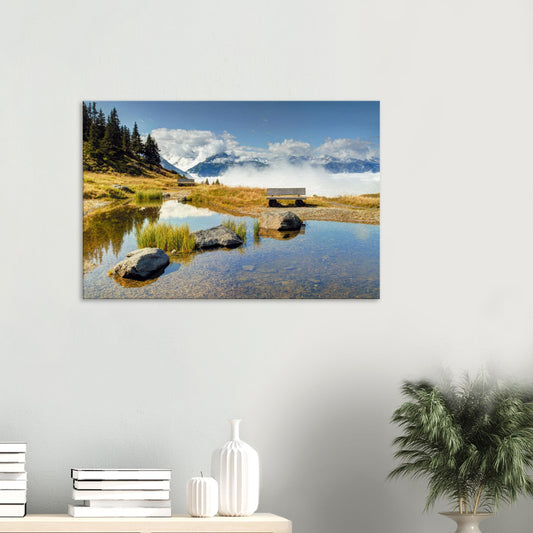 Canvas print of the Panoramabahn in Austria featuring a tranquil pond, mountain bench, and clouds drifting below majestic alpine peaks.