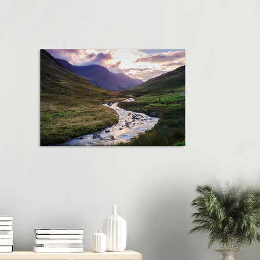 Canvas print of Honister Pass at golden hour with soft sunlight over rolling hills and a brook winding through the valley.
