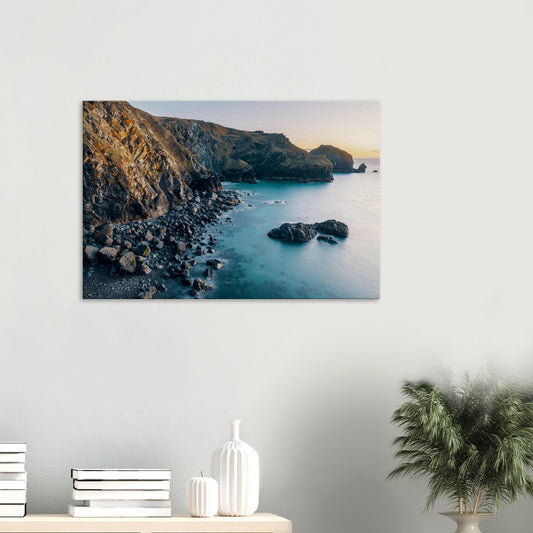 Golden sunset light casting a warm glow over Mullion Cove’s rugged Cornish cliffs