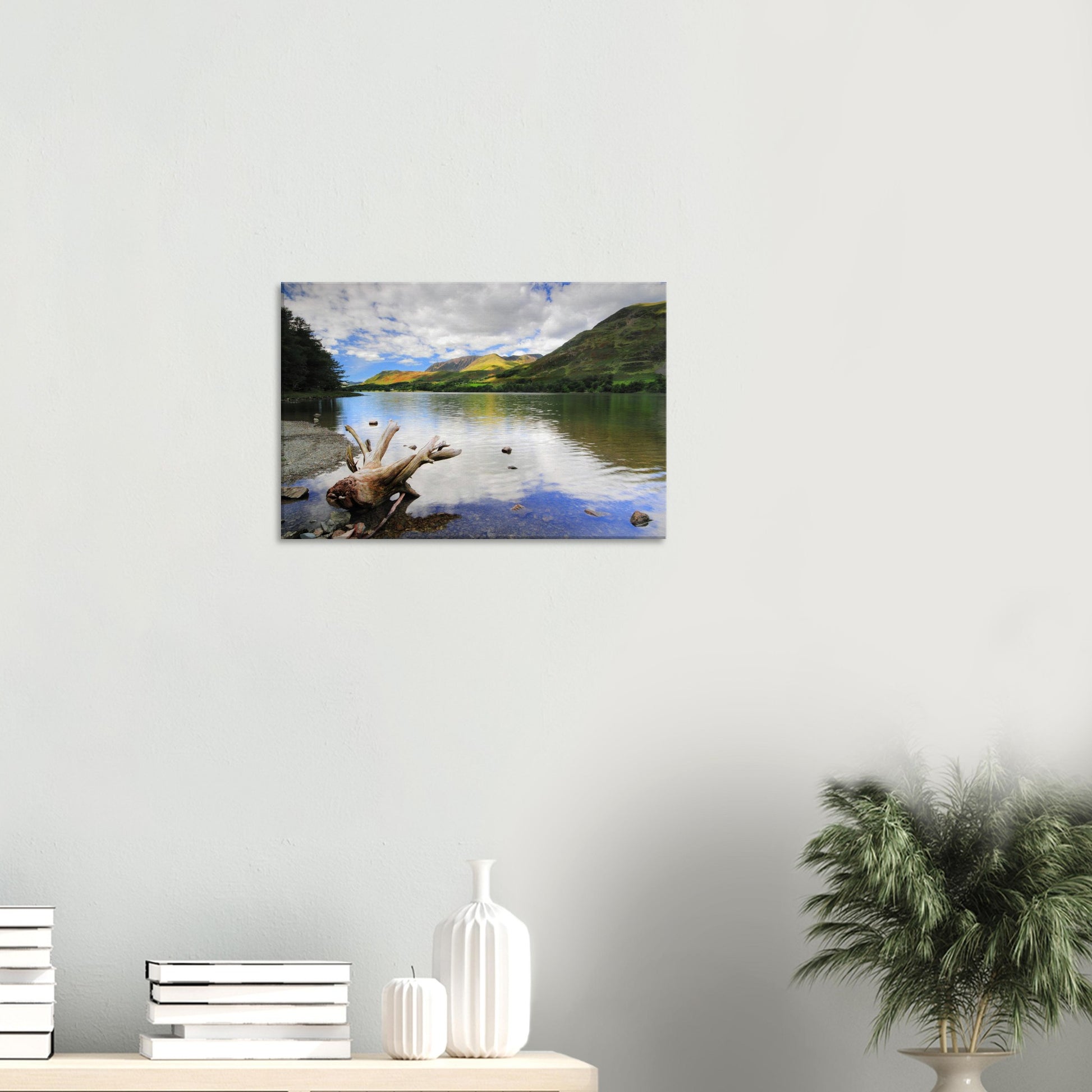 Serene landscape canvas of Buttermere Lake featuring a weathered driftwood piece against tranquil water and vibrant green hills under a partly cloudy sky.