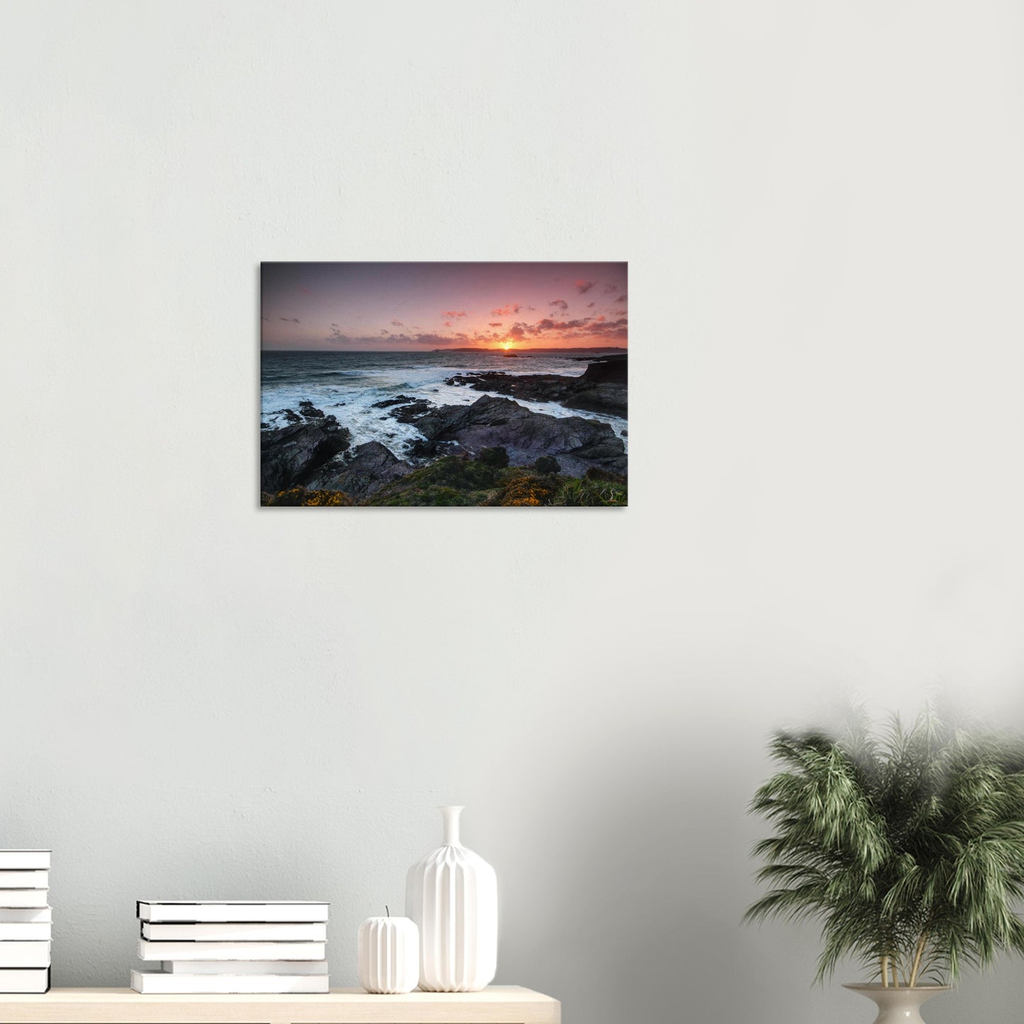 Canvas print of Heybrook Bay’s dramatic sunset with glowing sea, silhouetted rocks, and delicate wildflowers on the cliffside.