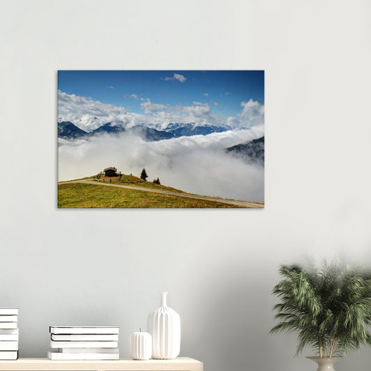 Canvas print of the Panoramabahn at Resterhöhe in Austria, featuring a mountain hut on a green hilltop above a sea of clouds with alpine peaks in the distance.