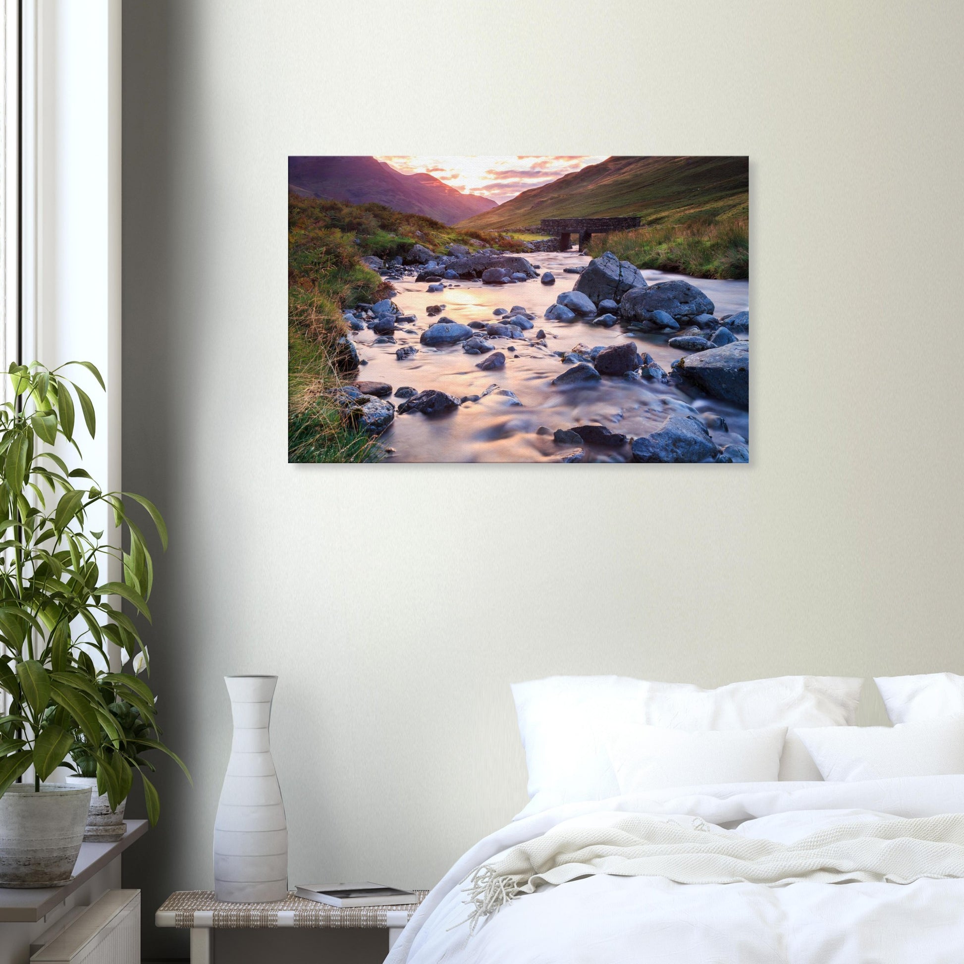 Landscape canvas of Honister Pass in warm sunset tones, featuring a calm stream winding through a rugged valley with a stone bridge.