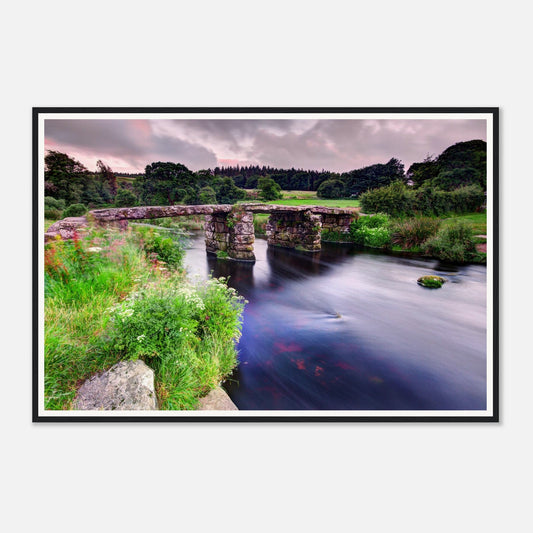 Historic stone clapper bridge over gentle river in Dartmoor