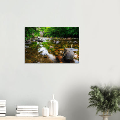 Peaceful riverside setting with light and shadow playing on smooth stones and rippling water