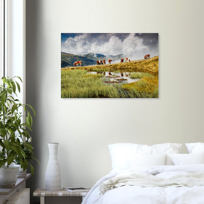 Peaceful alpine canvas print showing a grazing herd near a pond under a sky of drifting clouds and distant rugged peaks.