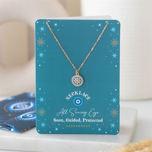 Gold-tone all seeing eye necklace on turquoise card with star accents and matching dark blue envelope.