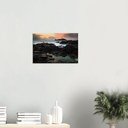 Vibrant sunset over Godrevy Lighthouse with layered cliff rocks, printed on high-quality canvas.