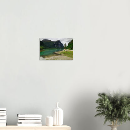 Peaceful alpine lake bordered by rich greenery, with a cascading waterfall and mountain peak in the distance