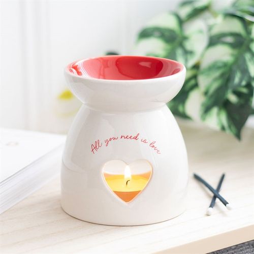 White ceramic oil burner with heart cut-out and "All you need is love" text, perfect for romantic and heartfelt gifting.