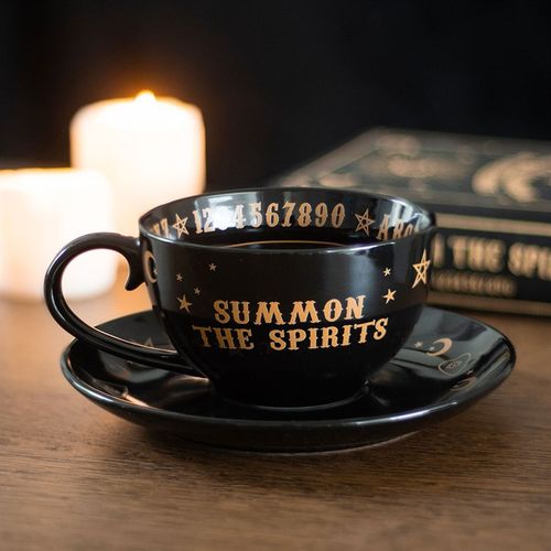 Ceramic teacup and saucer set with mystical talking board design in black and gold finish, perfect for tea leaf reading.