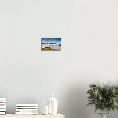 Canvas artwork of the Austrian Alps featuring a hillside hut above the clouds and dramatic alpine peaks in clear morning light.