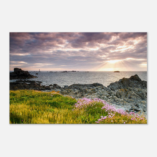 Sunset wall art of Pleinmont Point with glowing grasses, wildflowers, and Les Hanois Lighthouse under beams of fading light.