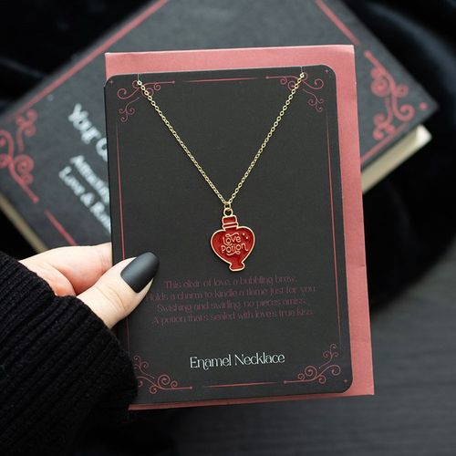 Gold-tone necklace with an enamel love potion charm, presented on a matching greeting card with an envelope.