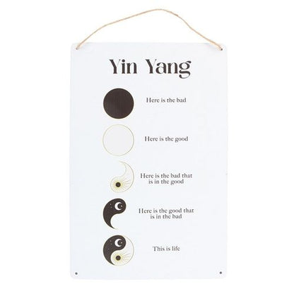 Hanging metal sign with a minimalist yin and yang design symbolising balance.